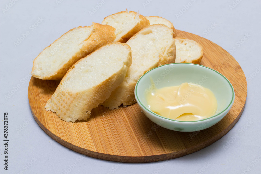 Butter on wooden holder surrounded by bread and milk on natural background Butter on wooden holder surrounded by bread and milk on natural background