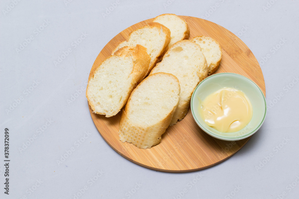 Butter on wooden holder surrounded by bread and milk on natural background