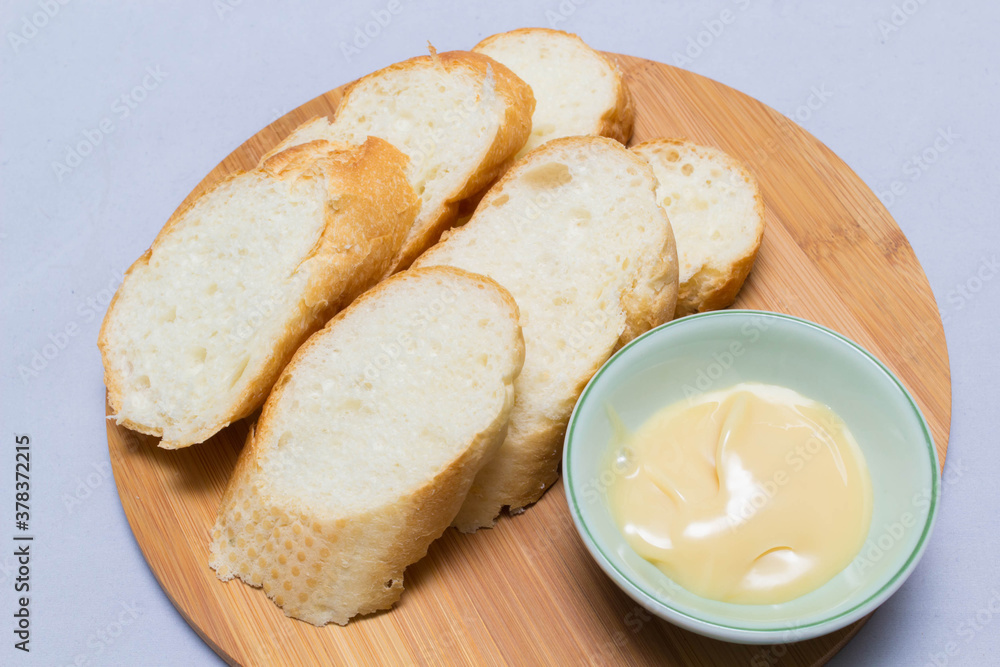 Butter on wooden holder surrounded by bread and milk on natural background