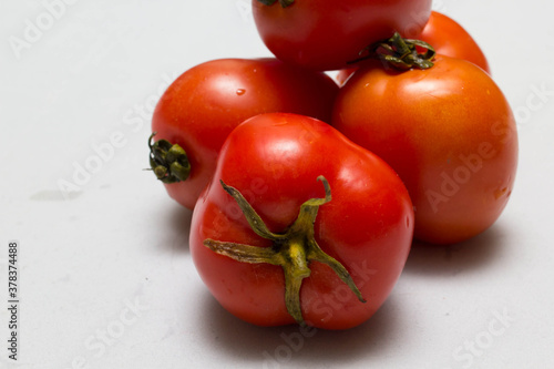 juicy red tomatoes in table cloth . caro background 