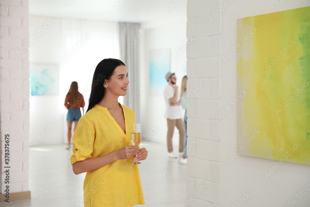 Young woman with glass of champagne at exhibition in art gallery Young woman with glass of champagne at exhibition in art gallery