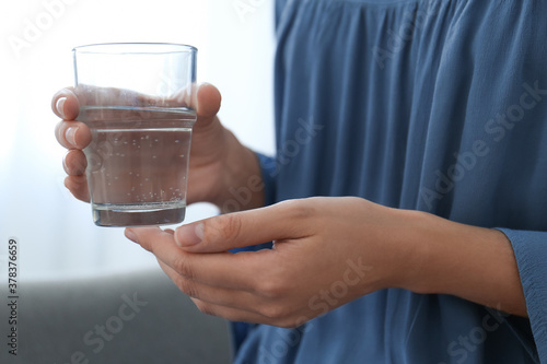 Woman holding glass of water at home, closeup