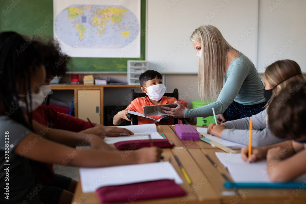 Female teacher wearing face mask teaching a disable boy wearing face mask at school Female teacher wearing face mask teaching a disable boy wearing face mask at school