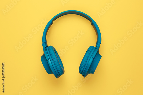 Blue headphone on yellow background. Music concept.
