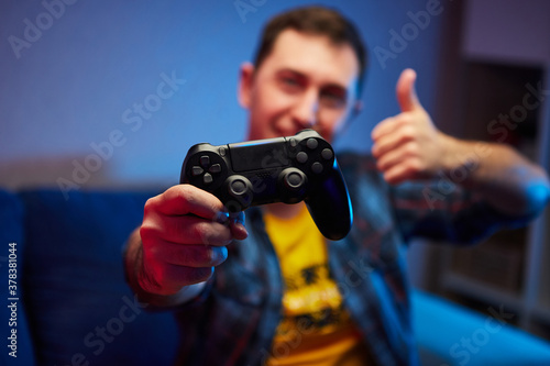 Portrait of crazy playful Gamer, boy enjoying Playing Video Games indoors sitting on the sofa, holding Console Gamepad in hands. Resting At Home, have a great Weekend