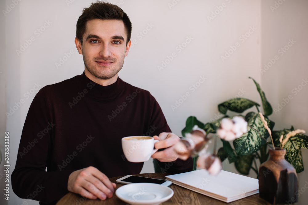 Confident young man drinking coffee in cafeteria Confident young man drinking coffee in cafeteria