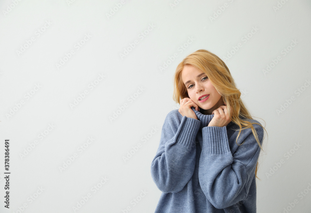 Beautiful young woman wearing warm blue sweater on light background. Space for text Beautiful young woman wearing warm blue sweater on light background. Space for text
