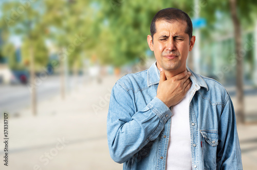 The man feels bad and coughs as a symptom of a cold or bronchitis on the outside. Health concept.