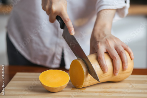 Female chef cutting pumpkin on a wooden board