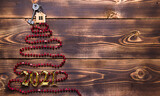 Key to the house with a keychain on top of Christmas tree made of red square beads. Flat lay on wooden background. Building or buying a house in new year. Mortgage, real estate rental. Space for text