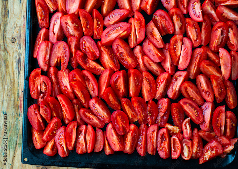 Tomatoes cut into wedges on a black pan. Tomato dishes. Tomato background. Tomatoes cut into wedges on a black pan. Tomato dishes. Tomato background.