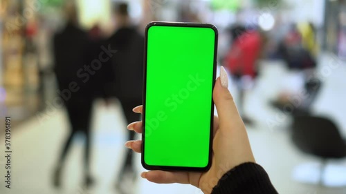 Wallpaper Mural Shopping center. Back view of brunette holding chroma key green screen smartphone watching content. Gadgets and contemporary people concept. Torontodigital.ca