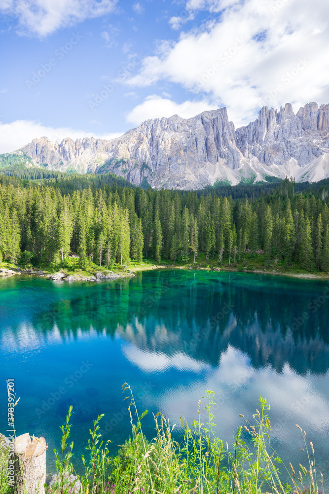 Carezza lake with wood barriers, Mountains in the back, turquoise water, (Lago di Carezza, Karersee) in Dolomites Alps. South Tyrol. Italy