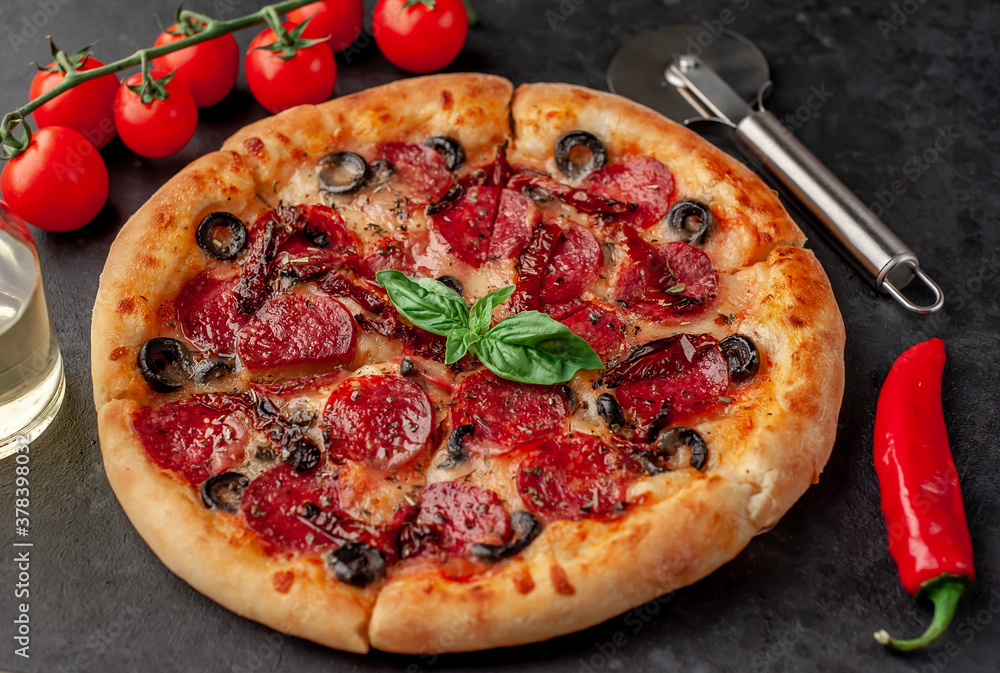 pizza pepperoni with salami sausages, mozzarella, olives, Provencal herbs, signature tomato sauce on a stone background