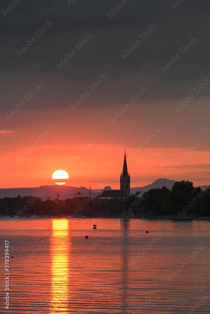 Germany, Baden-Wurttemberg, Radolfzell, Cloudy sky over Lake Constance at moody sunset with tower ofÔøΩRadolfzeller Munster in background Germany, Baden-Wurttemberg, Radolfzell, Cloudy sky over Lake Constance at moody sunset with tower ofÔøΩRadolfzeller Munster in background