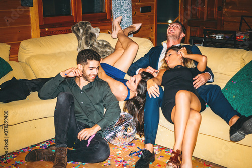 Cheerful drunk friends resting on sofa in party