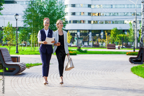 Two young girls walking in a summer park photo