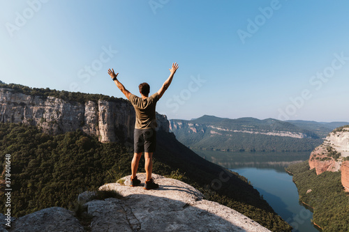 Man with arms raised standing on mountain against clear sky at Vilanova de Sau,  Catalonia, Spain photo