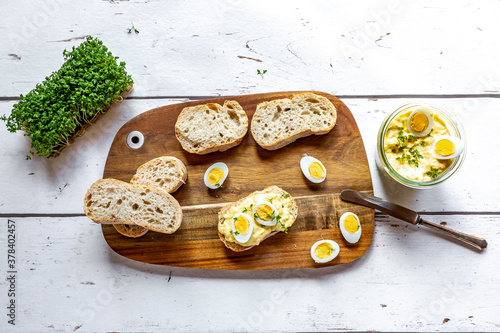 Sliced baguette and jar of homemade egg salad with cress photo