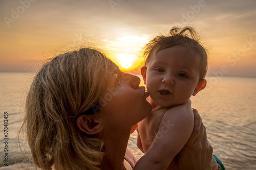 Vietnam,ÔøΩPhuÔøΩQuocÔøΩisland,ÔøΩOngÔøΩLang beach, Mother kissing baby in beach at sunset © Michael Runkel/Westend61