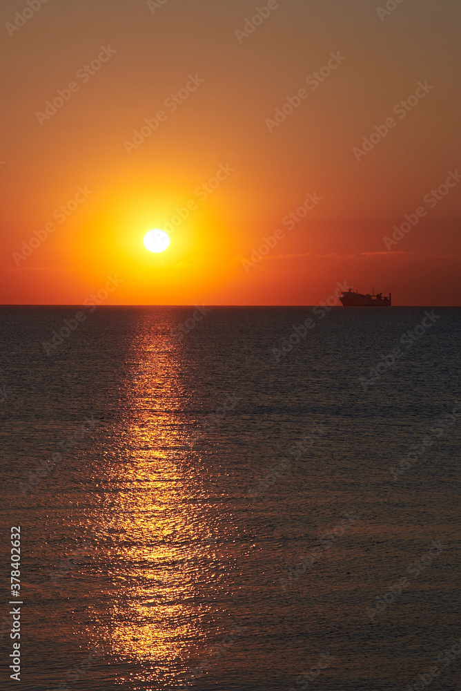 Sunset on the sea, ships standing on the horizon.