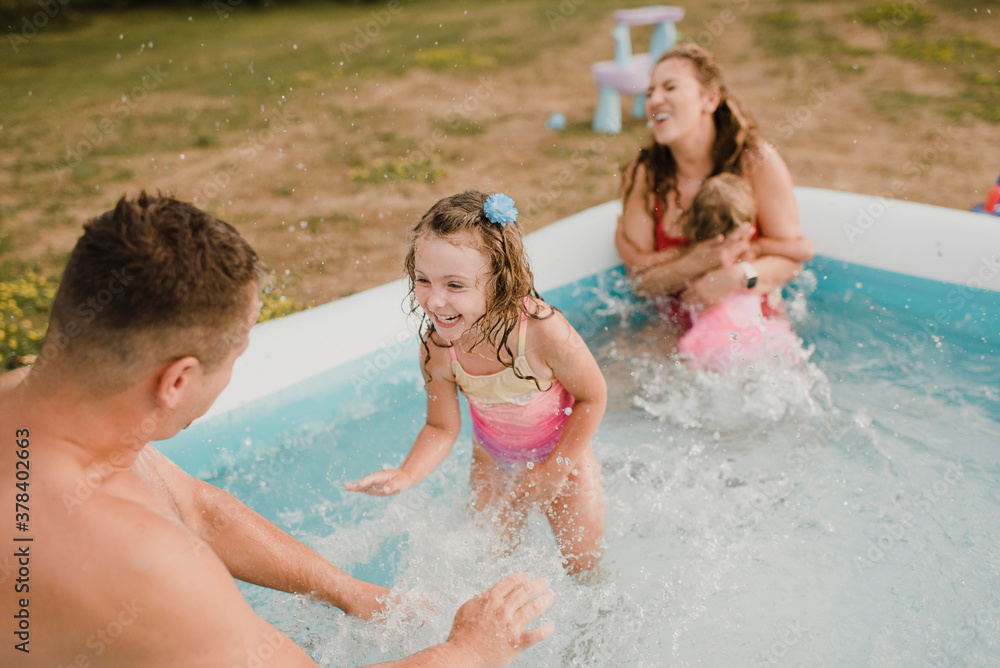 Happy family in an inflatable swimming pool in garden Happy family in an inflatable swimming pool in garden