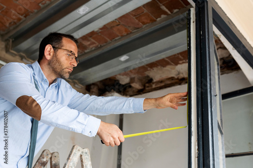 Architect using tape measure on window frame in a house under construction photo