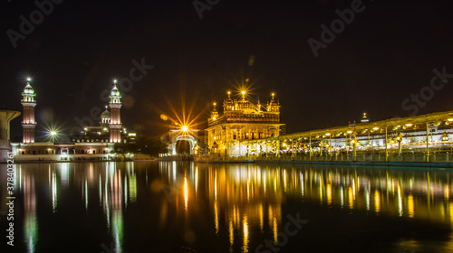 reflection of golden temple at night on water surface of nearby lake