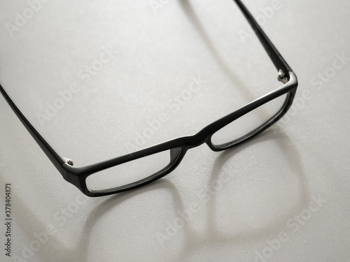 Black glasses and their shadow on gray background