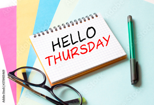 The Notepad with the text Hello Thursday is on colored paper with glasses and a pen