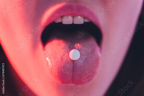beautiful girl with lsd on tongue in nightclub with pink smoke. photo