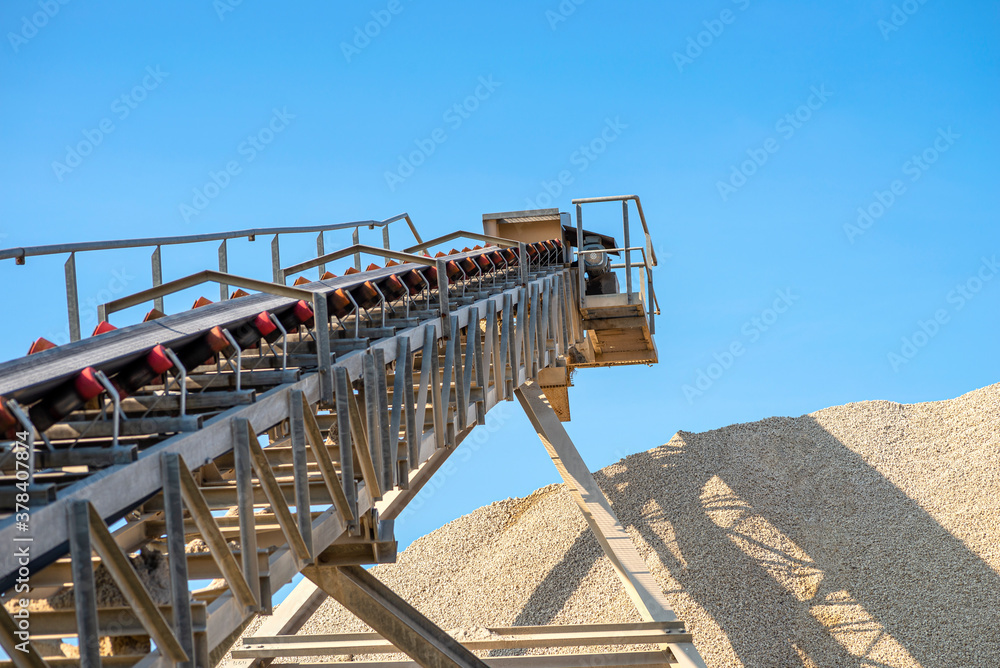 Φωτογραφία Conveyor belt over heaps of gravel against the blue sky at an industrial cement plant