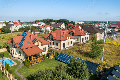Wallpaper Mural Aerial view of a new autonomous house with solar panels, water heating radiators on the roof, wind powered turbine and green yard with blue swimming pool. Torontodigital.ca