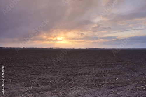 Sunset over a plowed agricultural field. Dramatic sky in the evening.