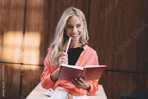 Cheerful young businesswoman with notebook in cafe