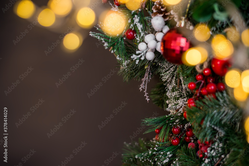 Christmas tree branch with red berries and decor on a dark background. Christmas background in a dark color with the lights.