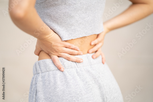 Woman wearing sweat pants and holding lower back