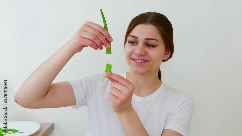 Young European brunette girl holds aloe vera green leaf. white background. smiling woman. Healthy lifestyle. Skincare and facial treatment concept. Natural alternative medicine. Young European brunette girl holds aloe vera green leaf. white background. smiling woman. Healthy lifestyle. Skincare and facial treatment concept. Natural alternative medicine.