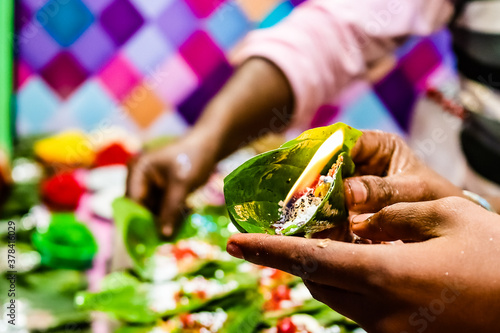 Obraz na plátně hand of a seller holding fire paan, betel leaf on flame.