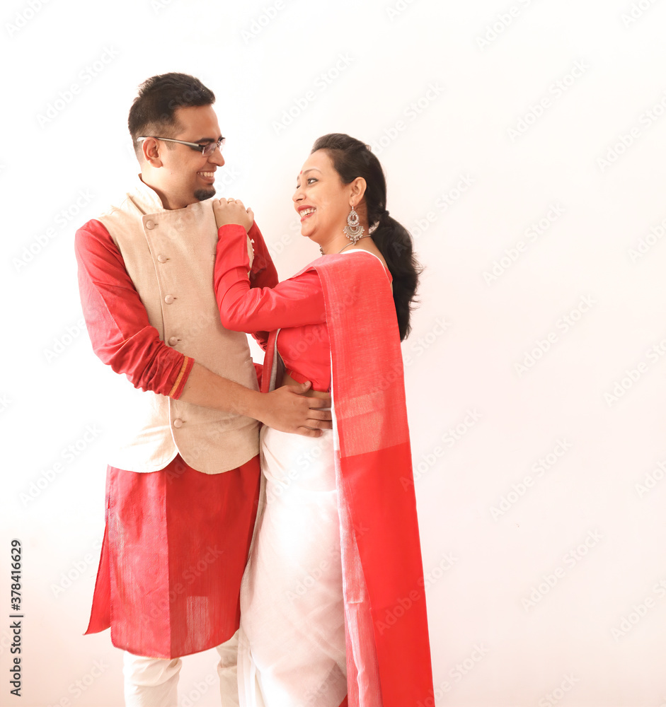 a young indian bengali assamese married romantic couple dressed in red and white ethnic indian dress, looking at each other and smiling