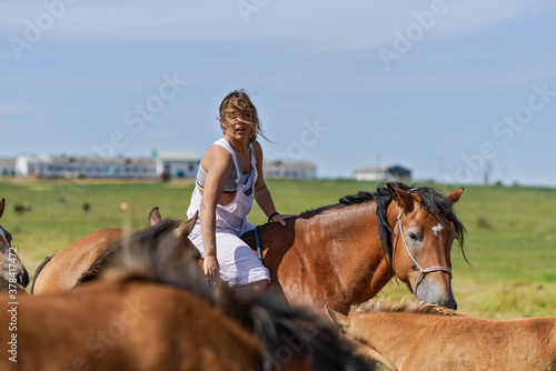 Young beautiful girl rides a horse on a farm field.