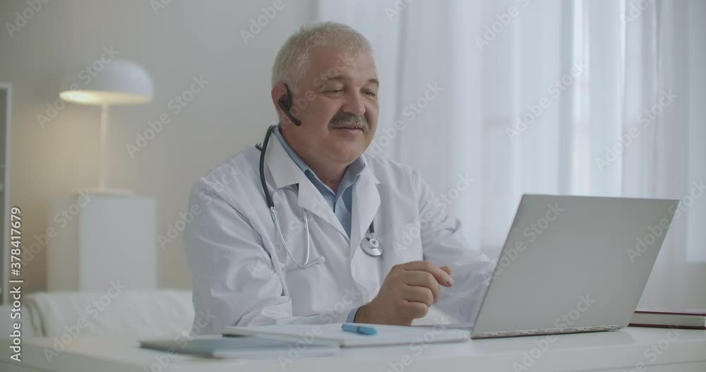 kind cheerful doctor is consulting online, working by internet with patient, chatting by video call from his laptop, modern telemedicine kind cheerful doctor is consulting online, working by internet with patient, chatting by video call from his laptop, modern telemedicine