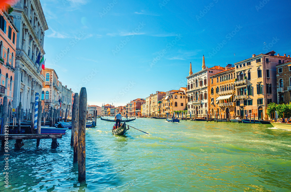 Venice cityscape with Grand Canal waterway, Venetian architecture colorful buildings, gondolier on gondola boat sailing Canal Grande, blue sky in sunny summer day. Veneto Region, Northern Italy.