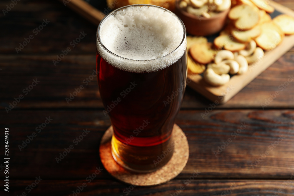 Glass of beer and snacks on wooden table Glass of beer and snacks on wooden table