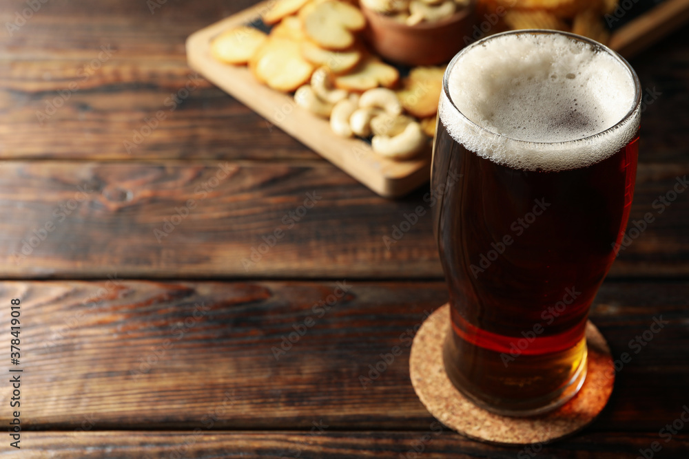 Glass of beer and snacks on wooden table Glass of beer and snacks on wooden table