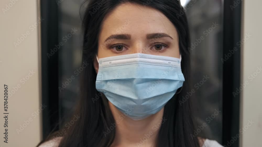 Portrait Of a young brunette woman in a protective, medical mask riding the subway, close-up. Portrait Of a young brunette woman in a protective, medical mask riding the subway, close-up.