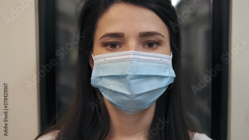 Portrait Of a young brunette woman in a protective, medical mask riding the subway, close-up.