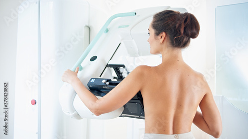 Healthy young woman doing cancer prophylactic mammography scan at hospital. photo