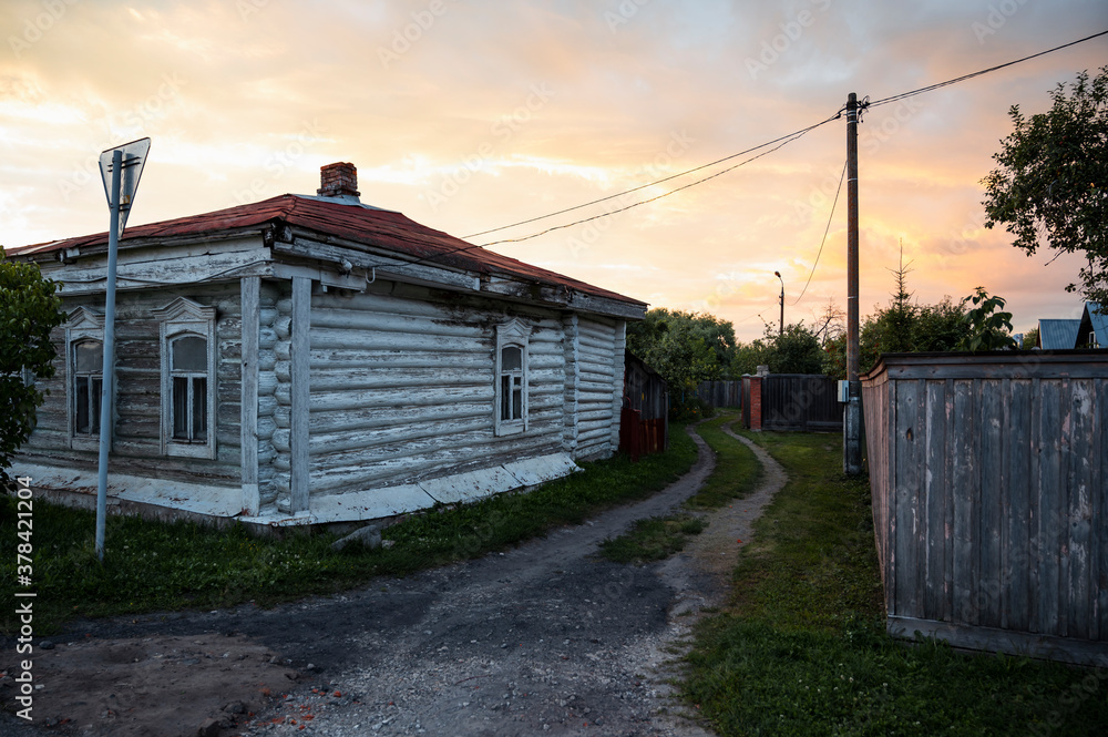 Wooden house and country road at sunset