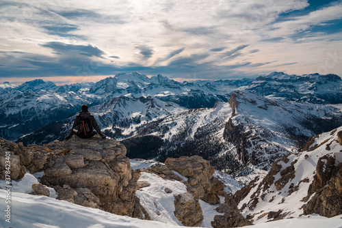 Young male hiker sitting down chilling relaxing facing awesome dolomites landscape in Cortina surroundings. Beautiful place icon, iconic mountain panorama 